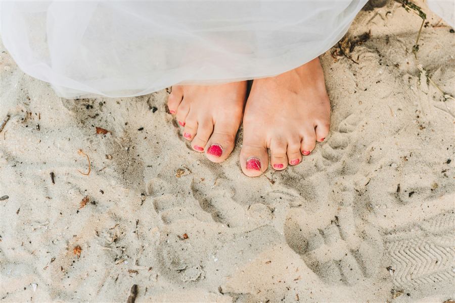 Soft-toned pedicure photo with pink polish on sand